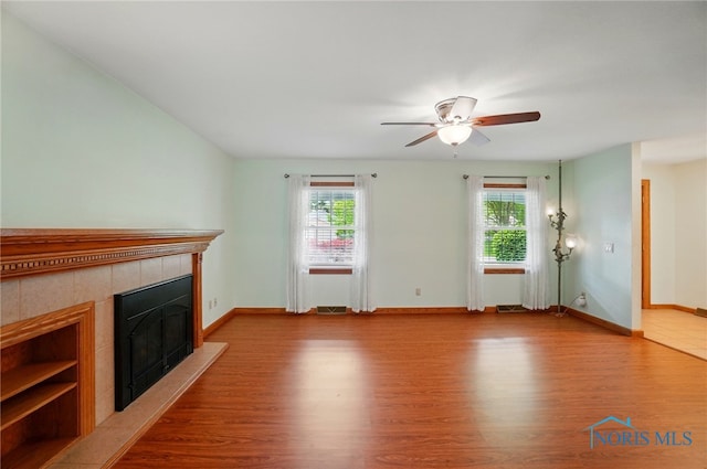 864 Cherry Ln, Waterville, OH 43566 - unfurnished living room featuring wood finished floors, a tiled fireplace, a ceiling fan, and baseboards