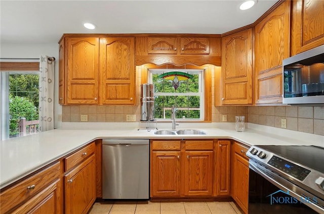 864 Cherry Ln, Waterville, OH 43566 - kitchen with stainless steel appliances, a sink, brown cabinetry, backsplash, and light countertops