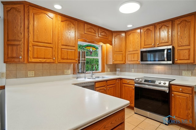 864 Cherry Ln, Waterville, OH 43566 - kitchen with appliances with stainless steel finishes, a sink, brown cabinetry, light countertops, and backsplash