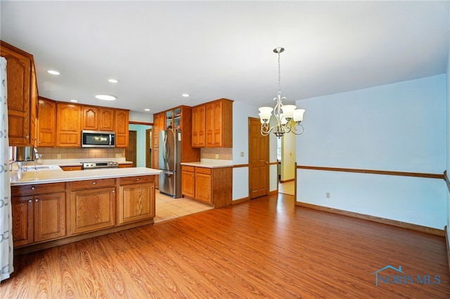 864 Cherry Ln, Waterville, OH 43566 - kitchen with appliances with stainless steel finishes, a chandelier, a sink, light wood-style flooring, and decorative backsplash