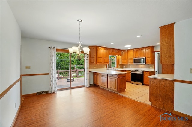 864 Cherry Ln, Waterville, OH 43566 - kitchen with stainless steel appliances, a chandelier, light wood-style floors, a sink, and light countertops