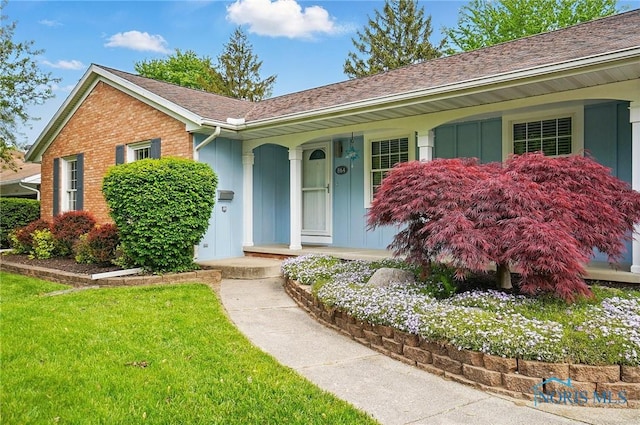 864 Cherry Ln, Waterville, OH 43566 - view of front of home with covered porch, board and batten siding, brick siding, a shingled roof, and a front yard