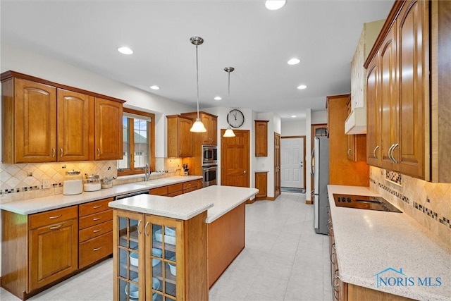 kitchen with a kitchen island, backsplash, appliances with stainless steel finishes, brown cabinetry, and light countertops