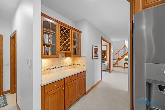 bar with backsplash, stairs, stainless steel fridge, and baseboards