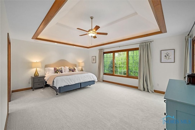 bedroom featuring a tray ceiling, baseboards, light carpet, and a ceiling fan