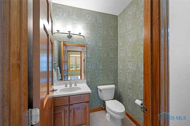 bathroom with toilet, vanity, tile patterned floors, and baseboards