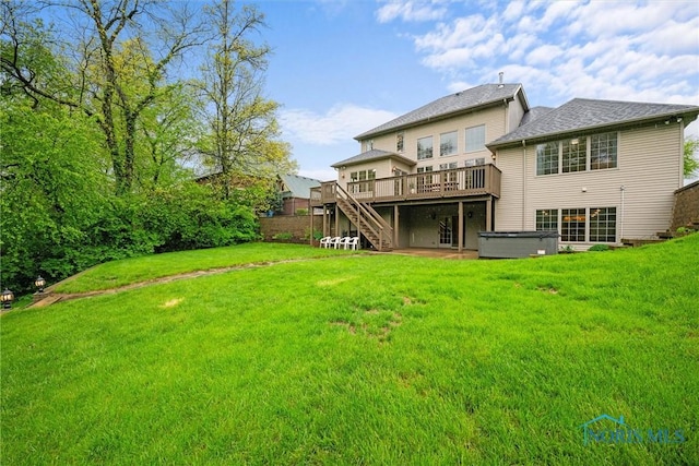 rear view of property featuring a hot tub, a wooden deck, stairs, and a yard