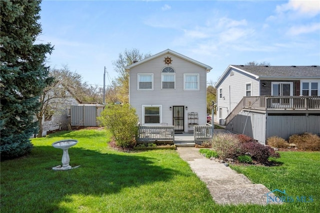 rear view of house featuring a deck and a yard