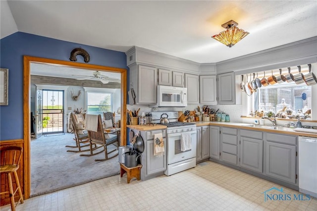 kitchen featuring a sink, gray cabinets, white appliances, light carpet, and light countertops