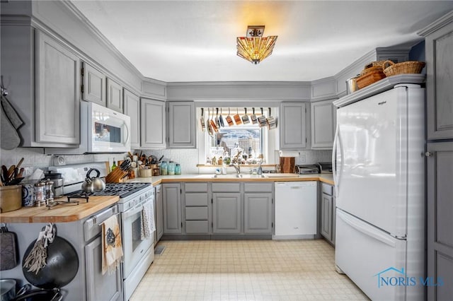 kitchen featuring a sink, gray cabinetry, butcher block counters, light floors, and white appliances