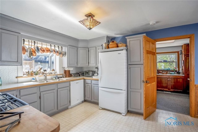 kitchen featuring white appliances, light countertops, backsplash, a sink, and gray cabinetry