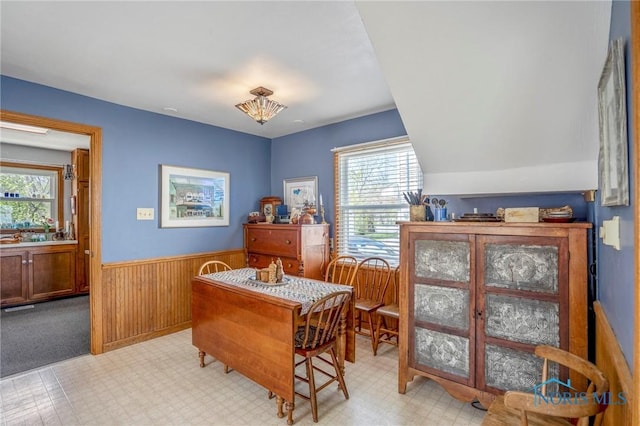 dining area featuring wainscoting, light floors, and wooden walls