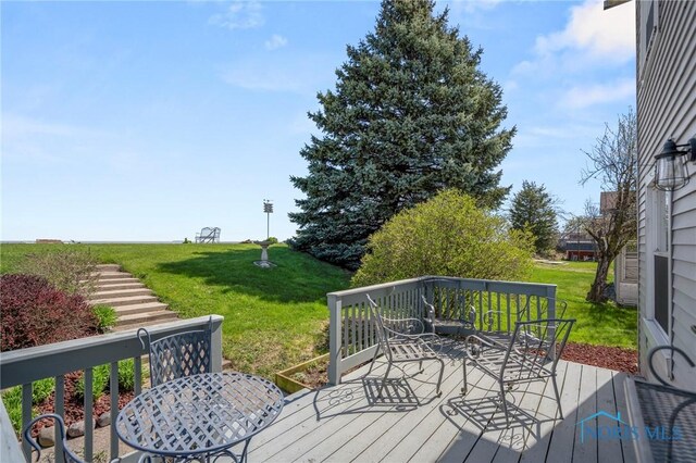 wooden deck featuring outdoor dining area and a lawn