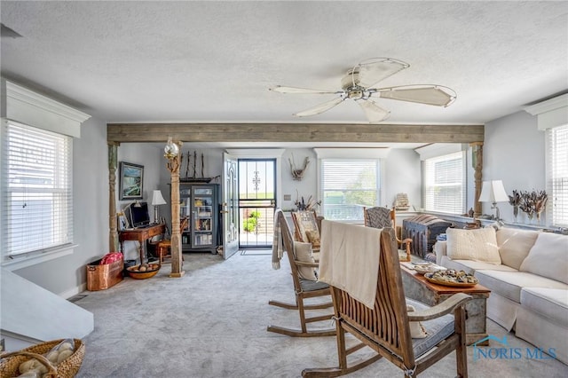 carpeted living area with a textured ceiling, a ceiling fan, and plenty of natural light
