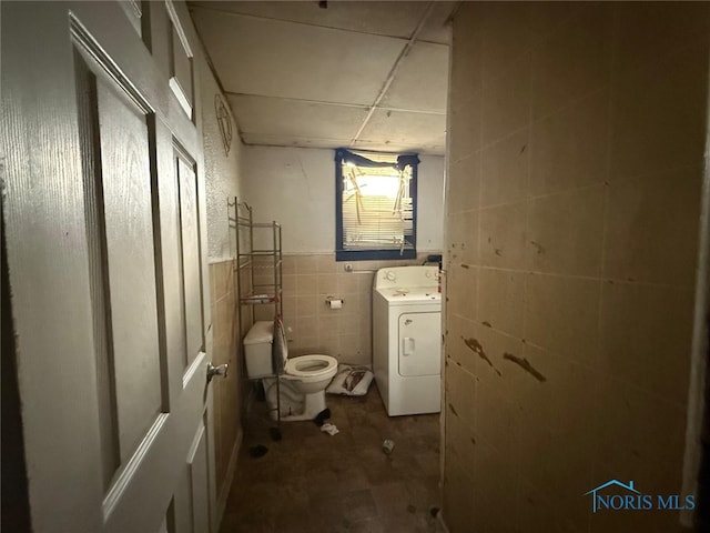 clothes washing area featuring tile walls, washer / clothes dryer, and laundry area