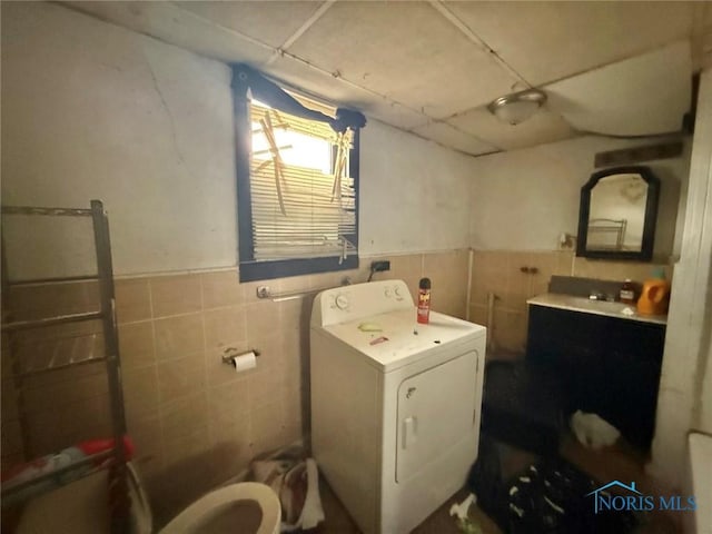 washroom featuring tile walls, washer / dryer, a wainscoted wall, and laundry area