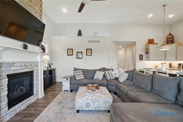 living area with visible vents, dark wood-style flooring, a fireplace, ceiling fan, and recessed lighting