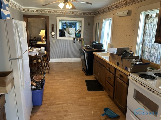 kitchen featuring white appliances, light wood-type flooring, a ceiling fan, baseboards, and wallpapered walls