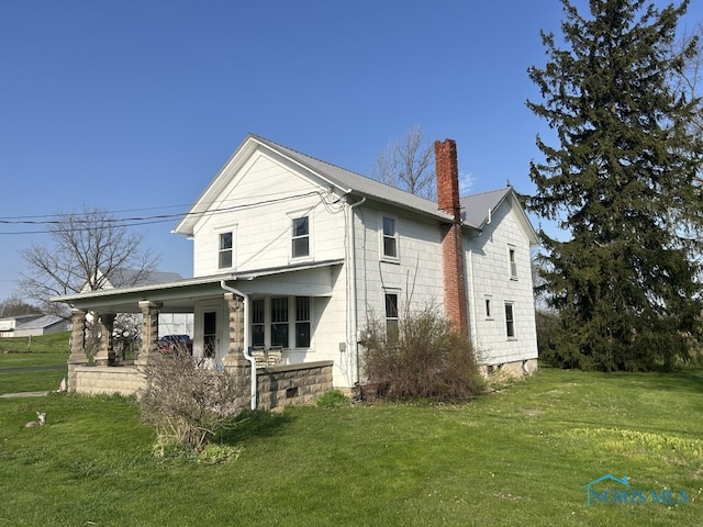 exterior space featuring a chimney, covered porch, and a yard