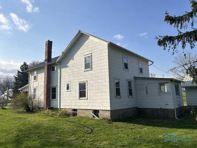 rear view of house with a yard and a chimney