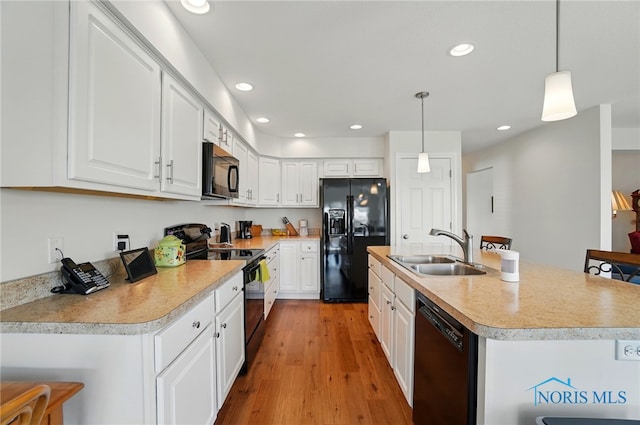 kitchen with black appliances, light wood finished floors, a sink, and white cabinets
