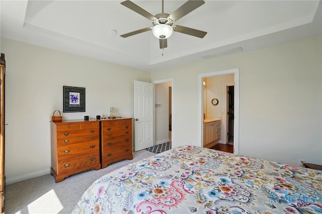 bedroom featuring a raised ceiling, baseboards, visible vents, and light carpet