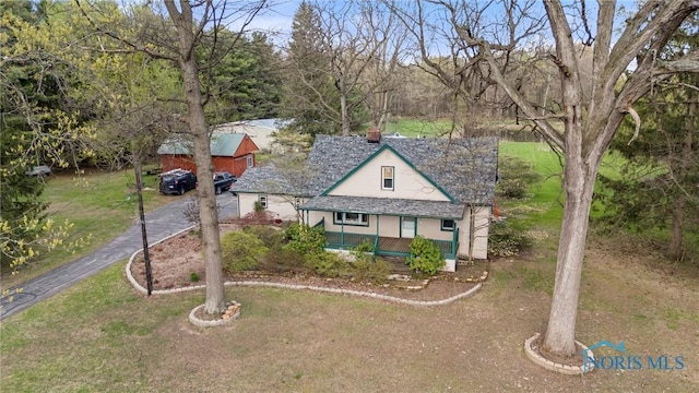view of front of property featuring a front yard, a chimney, covered porch, and aphalt driveway