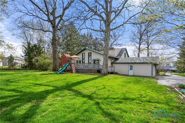 exterior space featuring a wooden deck, a playground, and a lawn
