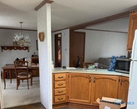 429 W Main St, Delta, OH 43515 - kitchen featuring freestanding refrigerator, brown cabinetry, stainless steel microwave, light countertops, and a chandelier