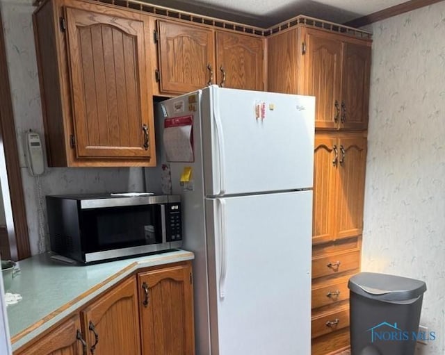 429 W Main St, Delta, OH 43515 - kitchen featuring stainless steel microwave, freestanding refrigerator, brown cabinetry, and wallpapered walls