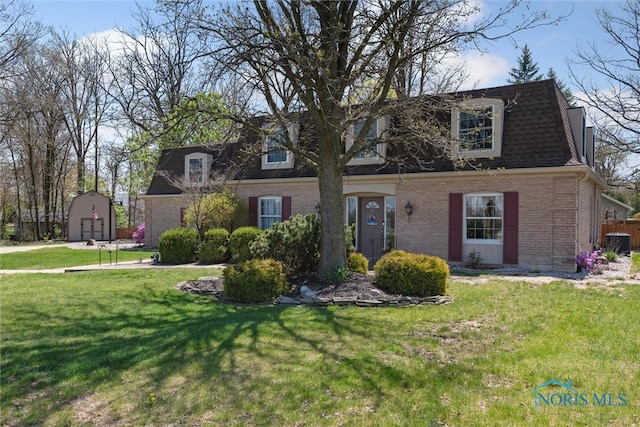 124 Miller Ave, Archbold, OH 43502 - view of front of home with brick siding, a storage shed, an outbuilding, a front lawn, and a shingled roof