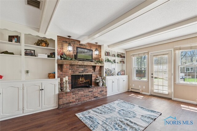 124 Miller Ave, Archbold, OH 43502 - living area featuring baseboard heating, wood finished floors, a brick fireplace, beamed ceiling, and a textured ceiling
