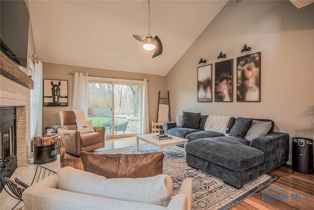 living room featuring a brick fireplace, ceiling fan, high vaulted ceiling, and wood finished floors