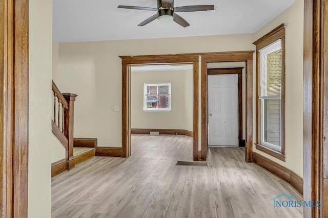 foyer with stairway, baseboards, a ceiling fan, and light wood-type flooring