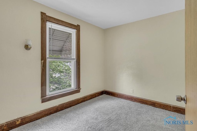 carpeted empty room featuring baseboards
