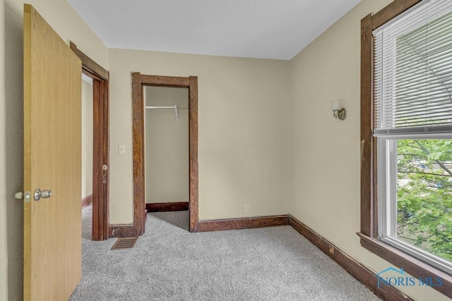 unfurnished bedroom featuring carpet flooring, baseboards, visible vents, and a spacious closet