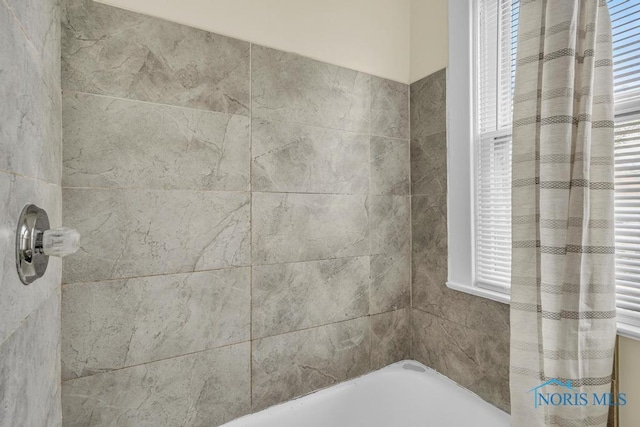 bathroom featuring a washtub, walk in shower, and plenty of natural light