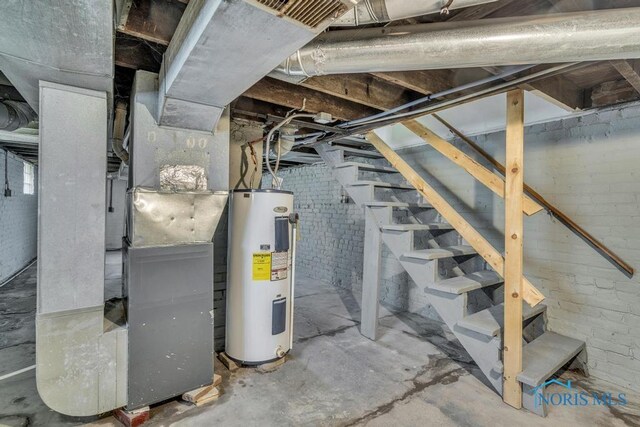 unfinished below grade area with heating unit, stairs, water heater, and brick wall