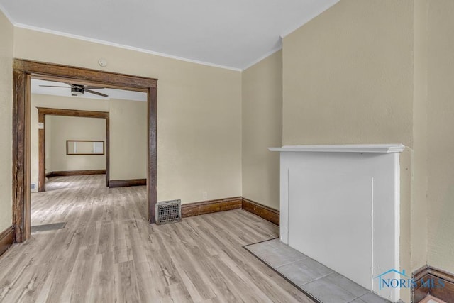 empty room featuring crown molding, light wood-style floors, baseboards, and visible vents