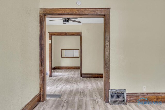 hallway featuring visible vents, baseboards, and wood finished floors