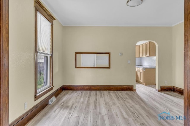 unfurnished room with crown molding, plenty of natural light, light wood-type flooring, and visible vents