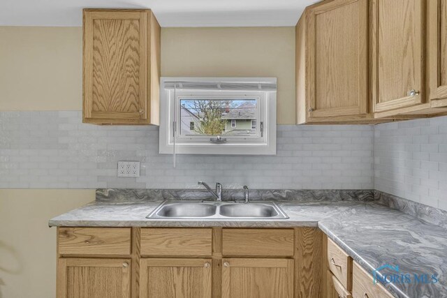 kitchen with light countertops, decorative backsplash, and a sink