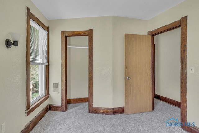 unfurnished bedroom with carpet floors, baseboards, and visible vents