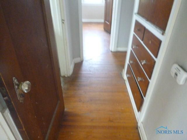 hallway featuring wood finished floors and baseboards