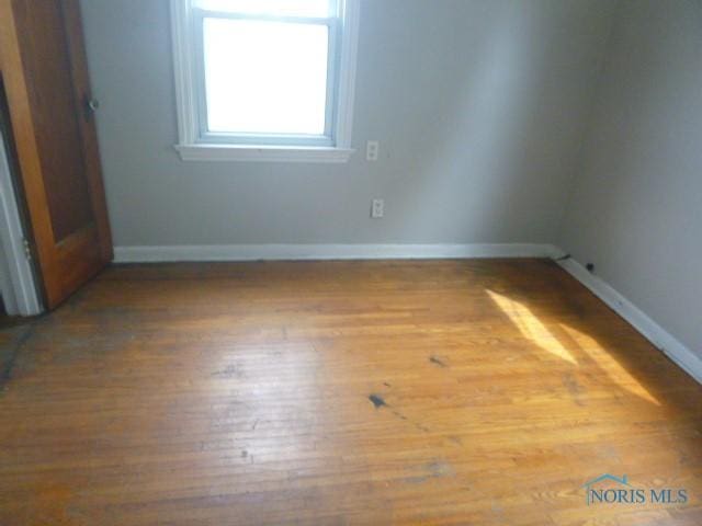 empty room featuring wood finished floors and baseboards