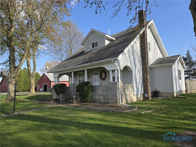 cape cod-style house featuring a chimney, a porch, roof with shingles, cooling unit, and a front yard