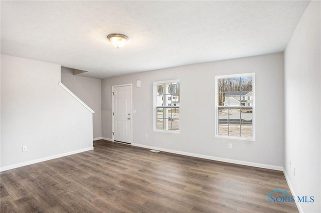 spare room with baseboards and wood finished floors