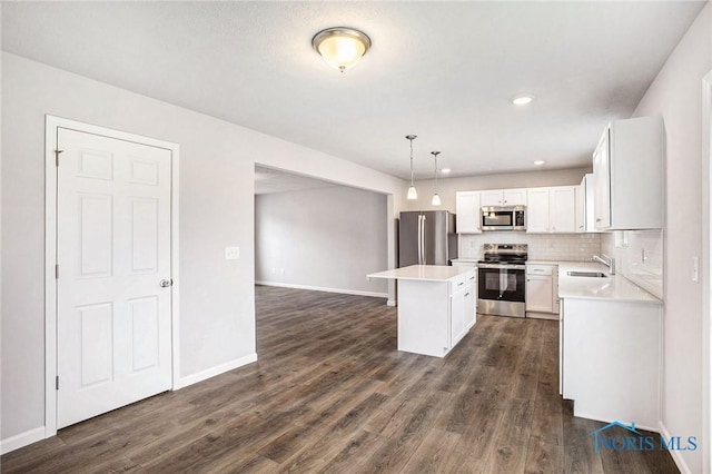 kitchen with appliances with stainless steel finishes, dark wood-style floors, a sink, and a center island