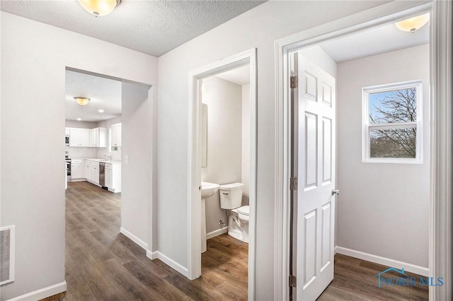hall featuring baseboards, visible vents, and dark wood-style floors