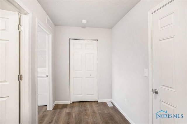 hall with baseboards, visible vents, wood finished floors, and washer / dryer